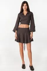 Minifalda color marrón oscuro, confeccionada en lino italiano, con diseño de cintura baja con caderín y bajo acampanado. Cierre invisible en el lateral.