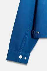 Chaqueta de cuello solapa y manga larga, de color azul, con bolsillos de vivo en los laterales, detalle de pliegues en la espalda y cierre frontal con cremallera. Cuenta con una etiqueta con logo bordado en el bajo.