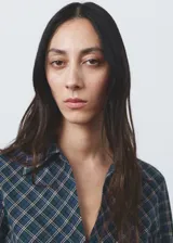 Blusa de algodón con diseño entallado y patrón de cuadros, cuello camisero, manga larga con puños abotonados y cierre frontal de ganchos con detalles fruncidos.