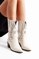 Botas tejanas de cuero color blanco hueso con bordados decorativos en hilo plateado, taco bajo y cierre lateral. Forradas en neoprene para mayor comodidad.