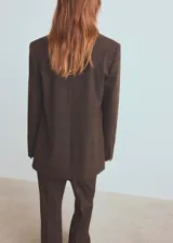 Blazer de corte sastre con diseño de doble botonadura, confeccionado en tejido con patrón de cuadros sutiles. Presenta solapas clásicas, bolsillos con solapa y una estructura entallada que aporta un estilo formal y sofisticado.