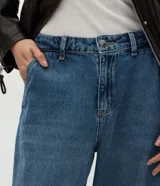 Pantalón de jean estilo aladín con cintura alta, corte amplio y piernas voluminosas que se ajustan en el bajo con puño elástico. Cuenta con pretina con presillas, cierre tradicional y bolsillos funcionales.