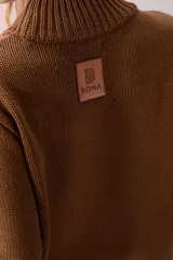 Sweater de punto color crema con cuello medio alto y silueta relajada. Presenta un diseño frontal con líneas en V decoradas con flecos largos de color marrón aplicados a mano.