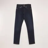 Pantalón de jean azul oscuro, corte slim, con bolsillos delanteros y traseros y costuras en color ocre.