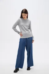 Sweater de lyocell al cuerpo, con cuello redondo a la base y mangas largas con detalle de botones en los puños.