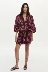 Blusa bordó con estampado floral en tonos rosados, confeccionada en algodón Swiss Dot, con mangas largas abullonadas y escote en V con botones frontales.
