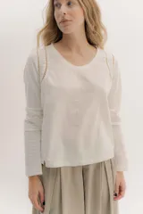 Remera de manga larga color blanco roto, con escote en V, detalle de doble entredos calado en las sisas y costuras verticales en el frente.