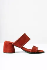Sandalias tipo mule de taco medio, confeccionadas en cuero gamuzado color terracota. Presentan dos tiras anchas con detalles de costuras pespunteadas en los bordes y taco cuadrado estable.