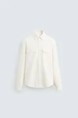 Sobrecamisa de corte regular confeccionada en denim de algodón, con cuello solapa, manga larga con puños abotonados y cierre frontal de botones. Presenta dos bolsillos frontales de plastrón con solapa y bajo con aberturas laterales.
