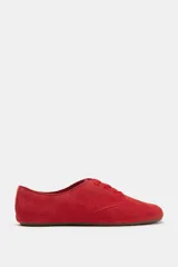 Zapatilla deportiva estilo blucher de piel color rojo, con pespuntes en el cuerpo, cierre mediante cordones y punta redonda.