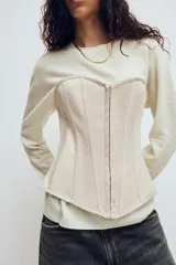 Top estilo corset de escote corazón y hombros descubiertos, con varillas interiores para estructura. Presenta cierre frontal con ganchos metálicos y ajuste posterior mediante cordones cruzados.