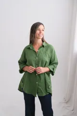 Camisa de lino de corte oversize, color verde seco, con cuello camisero, cierre frontal de botones de nácar, bolsillo frontal y mangas largas con sistema de ajuste.