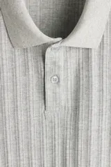 Remera polo de punto texturizado H&M, color gris, de manga corta, con cuello, tapeta con botones y corte ajustado.