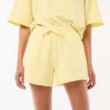 Pantalón corto de felpa color amarillo pastel, de tiro medio con cintura elástica ajustable mediante cordón y diseño holgado.