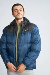 Campera puffer Mistral con diseño color block en azul y negro, cierre frontal completo, capucha desmontable y logo de la marca aplicado en goma en el pecho.