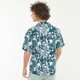 Camisa de manga corta con estampado de hojas y flores en tonos verde, azul y blanco. Tiene cuello clásico y cierre frontal con botones.