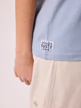 Remera celeste de corte holgado, con cuello redondo, manga corta y estampado frontal colorido de temática costera.