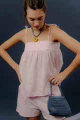 Conjunto de dos piezas confeccionado en lino color rosado, compuesto por una musculosa de corte amplio con breteles de lazo regulables y un short con elástico en la cintura y bolsillos delanteros redondeados.