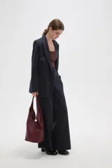 Bolso tipo hobo de gran tamaño, color negro, con diseño trenzado en la parte frontal y base lisa. Cuenta con un asa integrada para llevar al hombro.