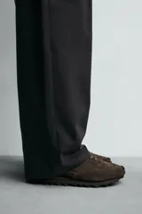 Zapatilla deportiva de hombre confeccionada en piel con acabado de serraje. Presenta un diseño de paneles combinados, cierre con cordones y suela dentada de goma.