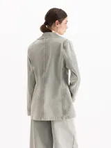 Blazer de denim color gris con lavado gastado, solapas clásicas, cierre frontal de un botón y bolsillos con tapa.