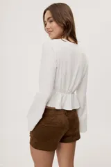 Short de tiro bajo con textura efecto gamuza color beige, bolsillos delanteros y detalle de cordones entrecruzados en la parte frontal.