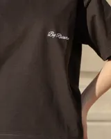 Remera de algodón color negro, de corte holgado y manga corta, con cuello redondo y logo bordado en tipografía cursiva en el pecho.