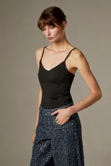 Body negro con tirantes finos, escote en V pronunciado y corte ajustado al cuerpo, con detalles bordados sutiles.