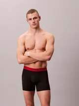 Pack de tres boxers largos Calvin Klein confeccionados en microfibra elástica. Presentan una cintura elástica con el logo de la marca en contraste, disponible en tres colores diferentes: negro con letras blancas, negro con letras negras y negro con letras rojas.