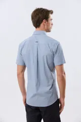 Camisa de manga corta de algodón en color celeste con microdiseño geométrico a cuadros, cuello camisero y bolsillo frontal con logo bordado.