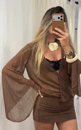 Vestido corto color marrón de tejido translúcido con textura, escote en V profundo y mangas largas acampanadas. Presenta un diseño ajustado en la parte inferior con frunces laterales.