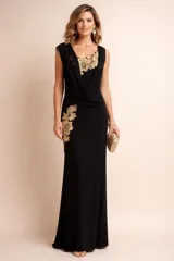 Vestido largo de gala color negro, con diseño drapeado en el escote y apliques de encaje floral dorado en el pecho y la cadera. Presenta una silueta entallada y sin mangas.