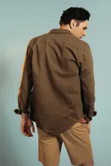 Bermuda de gabardina color tostado, de corte recto y largo por encima de la rodilla, con cierre y botón frontal.