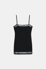 Vestido corto negro de escote recto y tirantes finos, con detalle de tachas metálicas circulares en el escote y en el ruedo.