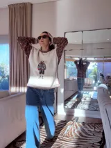 Sweater tejido con cuerpo en color crudo y mangas en lana multicolor. Presenta un diseño frontal estampado estilo vintage y detalles de tejido a crochet en cuello y puños.