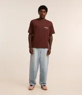 Pantalón baggy de jean celeste con bolsillos delanteros y traseros, cierre con botón y cremallera, y trabillas en la cintura.