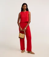 Pantalón recto de cintura alta confeccionado en tejido laise de algodón color rojo, con diseño de perforaciones y cierre lateral con cremallera.