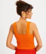 Blusa corta de punto color celeste, con textura arrugada tipo lastex, breteles anchos y escote cuadrado.