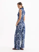 Pantalón azul con estampado de cadenas blancas en piqué de algodón elastizado, de tiro alto y botamanga amplia, con tiras laterales, bolsillos y tajos.