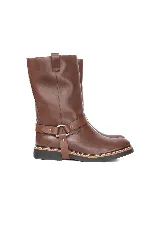 Bota de caña alta de cuero marrón, con diseño urbano y líneas limpias. Cuenta con una correa decorativa en el tobillo con argolla metálica y remaches plateados, suela de goma con costura reforzada y tirador trasero superior.