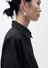 Camisa negra de manga corta, confeccionada en tejido de lino y algodón, con cuello camisero, diseño recto y cierre frontal de botones.