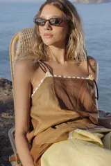 Vestido midi de lino color salmón, de corte amplio y silueta holgada. Presenta diseño con cortes irregulares y detalles de pasamanería en el escote y costuras. Cuenta con breteles dobles tipo cuerda y ruedo asimétrico.