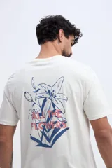 Remera de algodón color off-white, de corte regular, con estampa en la espalda de flores en tonos azules y la frase 'All the flowers' en color rojo.