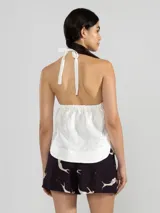 Top halter azul marino confeccionado en lino italiano con hilo metalizado, que aporta un sutil efecto de brillo y una textura natural. El escote halter se ajusta mediante un cordón al cuello, donde se ubica la insignia del tigre Polonio, fácilmente removible al deslizar el cordón.