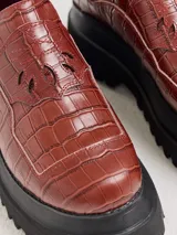 Mocasines de plataforma alta con diseño de estilo rebelde. Presentan un estampado de cuadros en tonos violeta y amarillo, confeccionados en lona con detalles en cuero. Cuentan con una suela robusta y elásticos laterales ocultos para facilitar el calce.