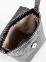 Porta celular de cuero marrón con diseño trenzado y solapa frontal, cuenta con correa larga regulable.