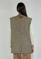 Chaleco largo color crudo con solapas, sin mangas y cierre con dos botones.