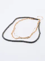 Collar dorado de tres hilos, uno de cuentas azul marino con detalles dorados, uno de eslabones grandes y uno de eslabones pequeños.