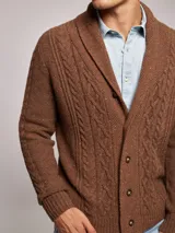 Cárdigan de punto color marrón con diseño de ochos, cuello smoking y cierre frontal con botones. Presenta un acabado jaspeado con motas de colores.