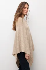 Capa tejida de corte asimétrico en tono beige, con escote redondo y diseño holgado.